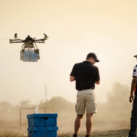 Drone holding Skybox hovering during Cobra Gold military exercise with Potter operator with control and Thai military officer in foreground