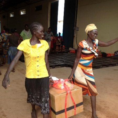 female Sudanese aid workers carrying box of supplies at SkyLIFE staging facility in Africa